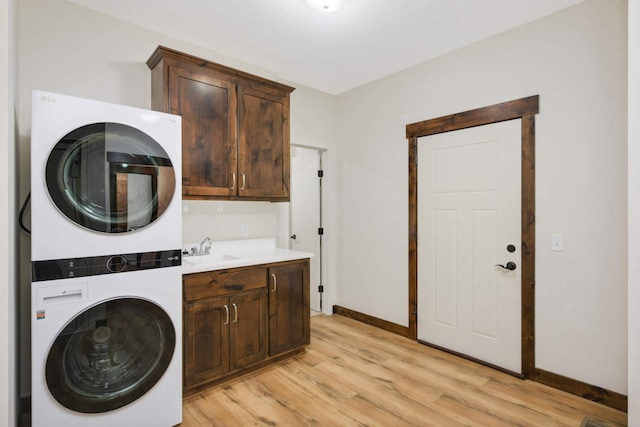 12891 Xylite St NE, Blaine, MN 55449 - laundry room with cabinet space, stacked washer and dryer, a sink, light wood-style floors, and baseboards