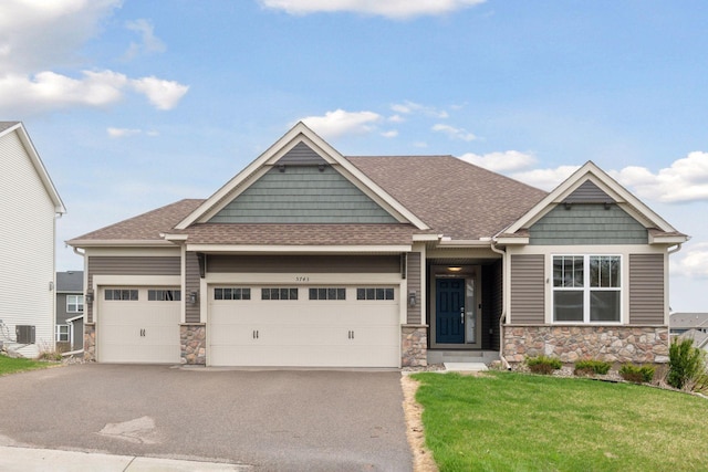 5743 Meridian Way NE, Prior Lake, MN 55372 - craftsman-style house with stone siding, a front lawn, a shingled roof, asphalt driveway, and a garage