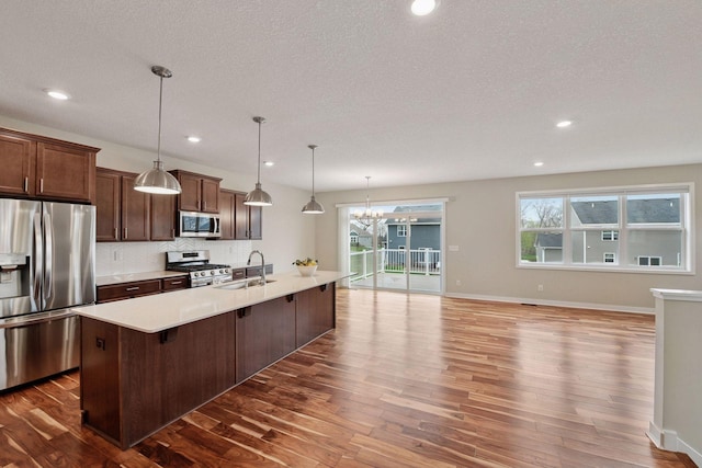 5743 Meridian Way NE, Prior Lake, MN 55372 - kitchen featuring appliances with stainless steel finishes, a sink, dark wood-type flooring, a chandelier, and light countertops
