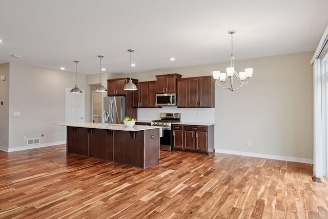5743 Meridian Way NE, Prior Lake, MN 55372 - kitchen with stainless steel appliances, light wood-style flooring, light countertops, a kitchen island with sink, and recessed lighting