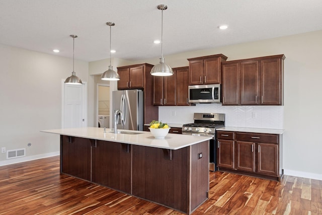 5743 Meridian Way NE, Prior Lake, MN 55372 - kitchen with appliances with stainless steel finishes, a kitchen island with sink, light countertops, dark wood-type flooring, and recessed lighting