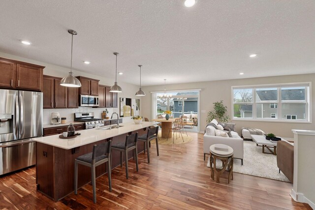 5743 Meridian Way NE, Prior Lake, MN 55372 - kitchen with stainless steel appliances, dark wood-style flooring, a kitchen breakfast bar, a sink, and an island with sink