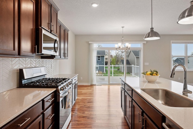 5743 Meridian Way NE, Prior Lake, MN 55372 - kitchen featuring stainless steel appliances, a sink, backsplash, wood finished floors, and pendant lighting