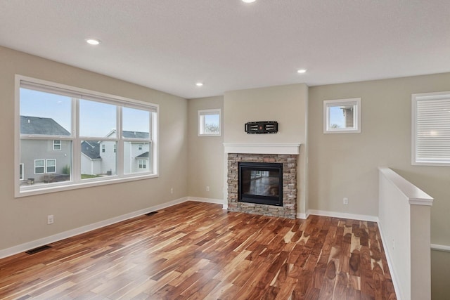 5743 Meridian Way NE, Prior Lake, MN 55372 - unfurnished living room featuring wood finished floors, healthy amount of natural light, a stone fireplace, baseboards, and recessed lighting