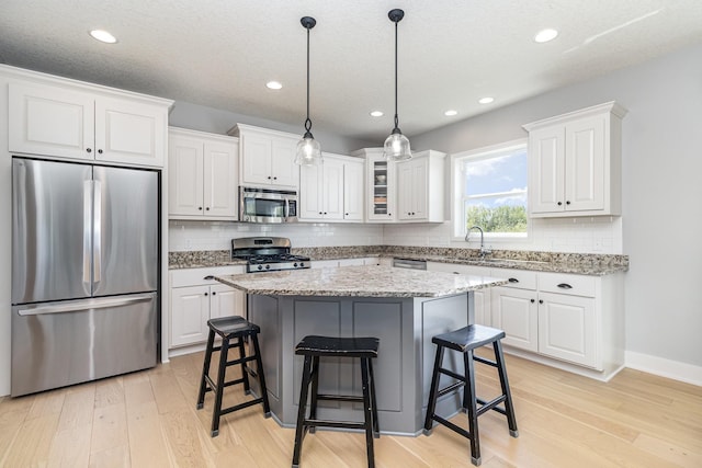 kitchen with stainless steel appliances, a breakfast bar, white cabinetry, light wood-type flooring, and recessed lighting