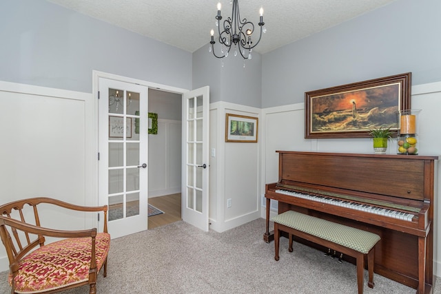 sitting room with french doors, a chandelier, carpet floors, and a textured ceiling