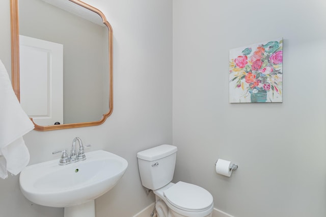 bathroom with a sink, baseboards, and toilet
