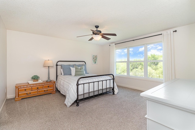 bedroom featuring light carpet, baseboards, a ceiling fan, and a textured ceiling