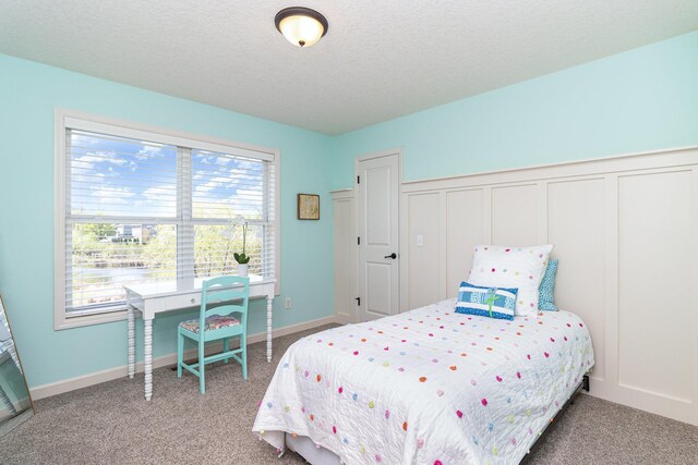 bedroom featuring carpet floors, multiple windows, a textured ceiling, and a wainscoted wall