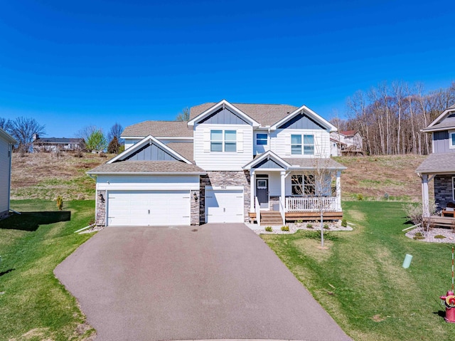 craftsman-style home with stone siding, board and batten siding, a porch, a front yard, and driveway