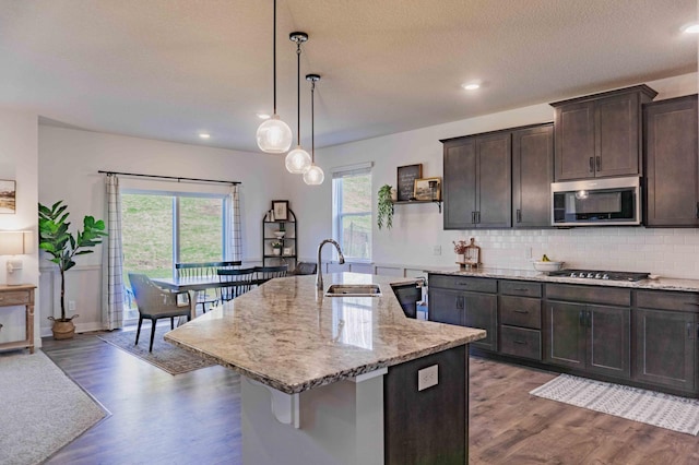 kitchen with dark wood-style flooring, dark brown cabinets, tasteful backsplash, a sink, and stainless steel appliances