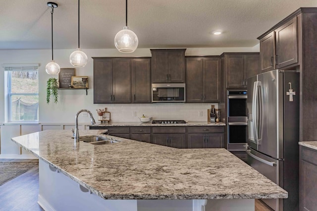 kitchen with a sink, appliances with stainless steel finishes, wood finished floors, and dark brown cabinets