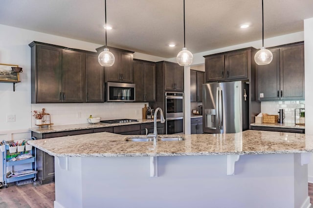kitchen with dark brown cabinets, appliances with stainless steel finishes, a sink, and wood finished floors