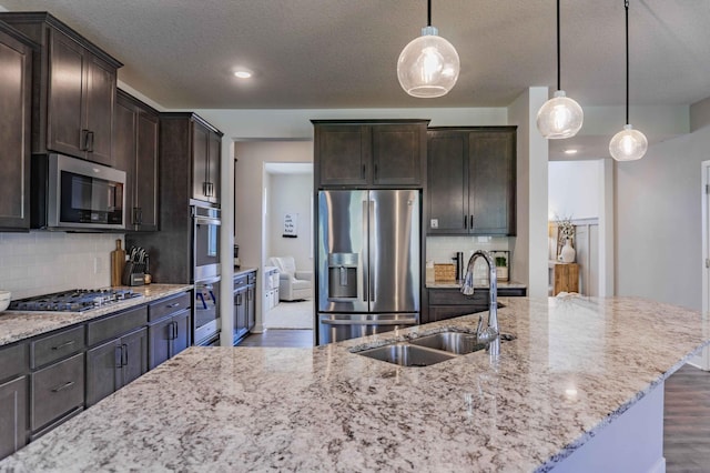 kitchen featuring a sink, appliances with stainless steel finishes, light stone counters, and wood finished floors