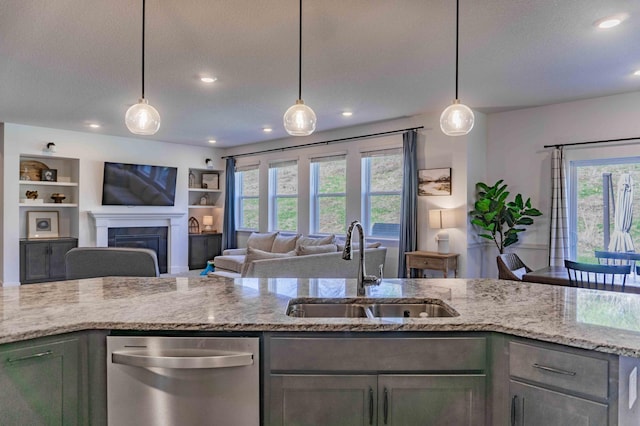 kitchen with a sink, dishwasher, a healthy amount of sunlight, and light stone countertops