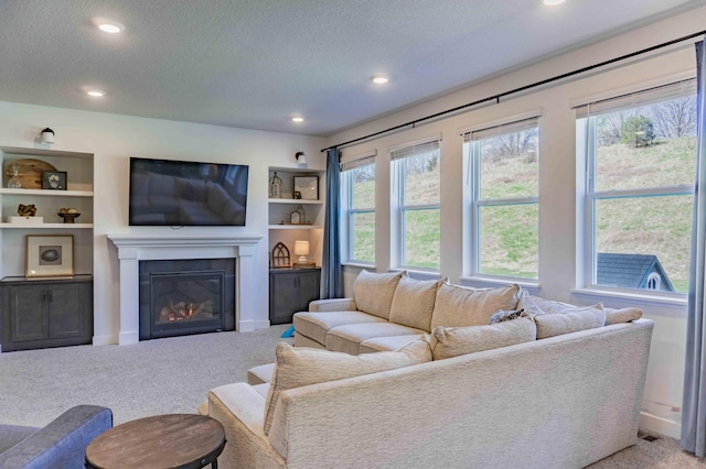 living room with a textured ceiling, baseboards, a glass covered fireplace, carpet, and recessed lighting