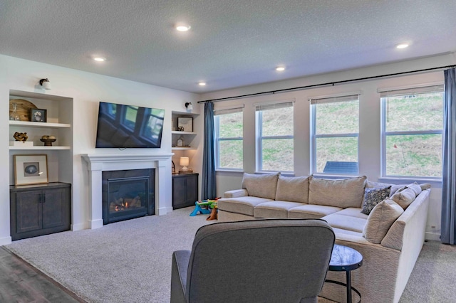 living area featuring a glass covered fireplace, recessed lighting, and a textured ceiling
