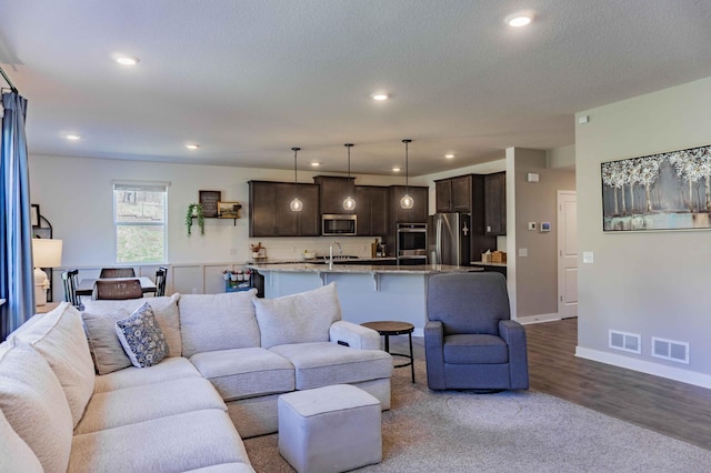 living room featuring recessed lighting, baseboards, visible vents, and wood finished floors