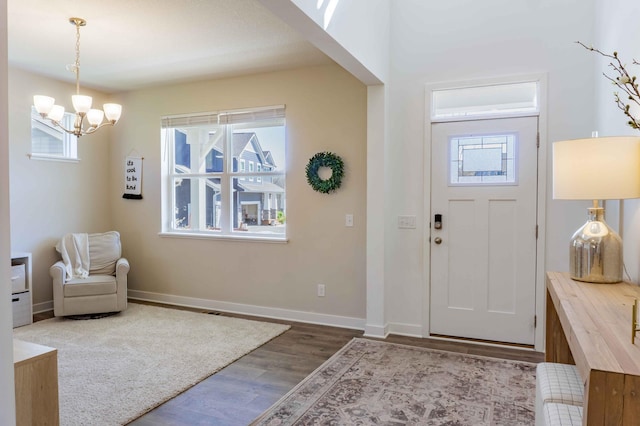 foyer entrance featuring plenty of natural light, baseboards, wood finished floors, and a notable chandelier