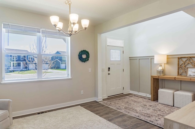 entryway featuring baseboards, wood finished floors, a chandelier, and visible vents