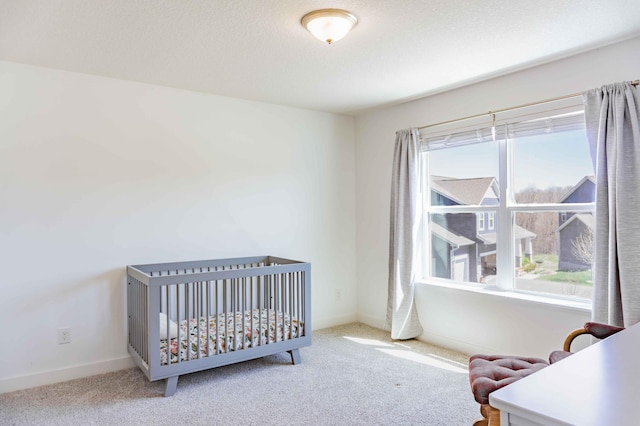carpeted bedroom featuring baseboards and a crib