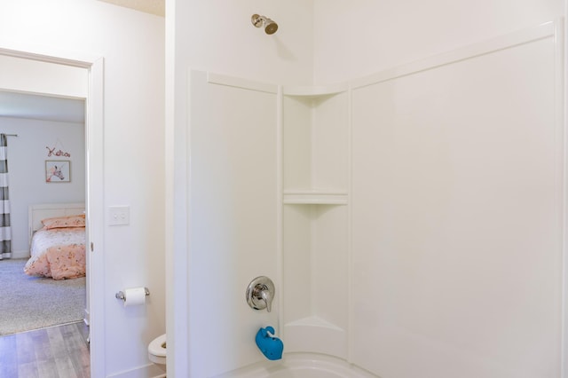 bathroom featuring wood finished floors, bathing tub / shower combination, and toilet