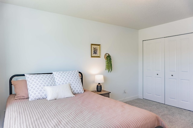 carpeted bedroom with a closet and baseboards