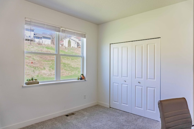 unfurnished bedroom with baseboards, multiple windows, light colored carpet, and visible vents