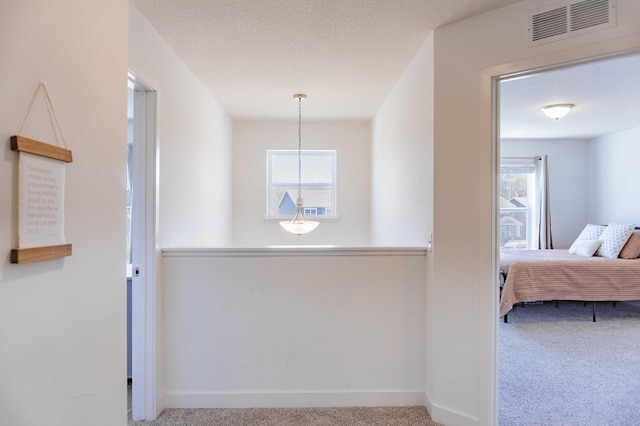 hallway featuring carpet floors, baseboards, and visible vents