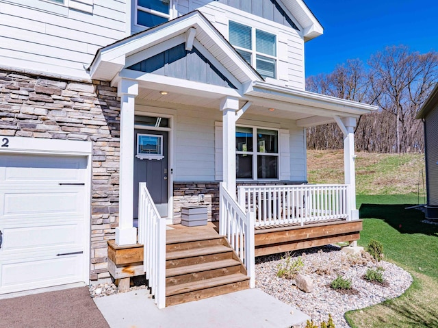 doorway to property with a porch, board and batten siding, a yard, an attached garage, and stone siding