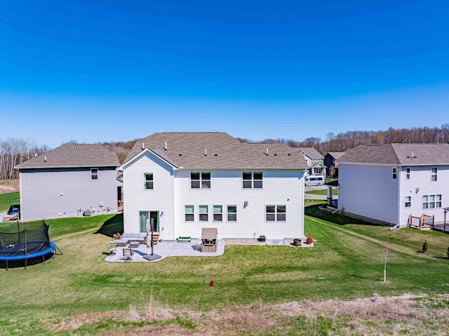 back of property featuring a lawn, a trampoline, and a patio area