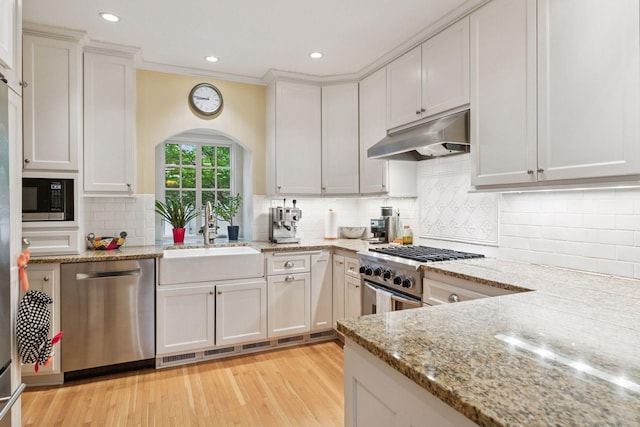 26 Mississippi River Blvd N, Saint Paul, MN 55104 - kitchen with appliances with stainless steel finishes, under cabinet range hood, a sink, arched walkways, and light wood finished floors