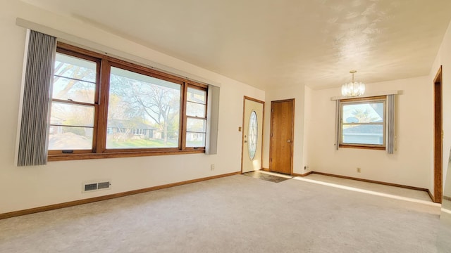 empty room with a chandelier, baseboards, and healthy amount of natural light