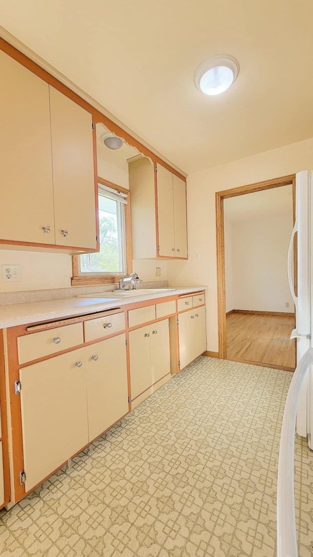 kitchen with light countertops, baseboards, and a sink
