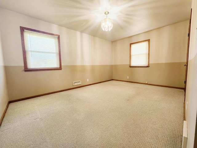 unfurnished room with plenty of natural light, carpet flooring, a chandelier, and baseboards