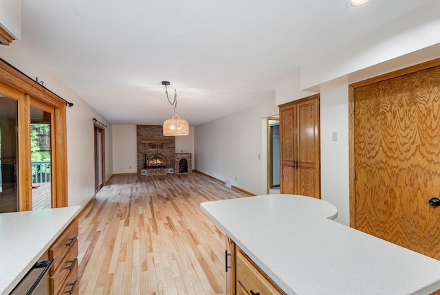 8762 Highwood Way, Apple Valley, MN 55124 - kitchen featuring light countertops, light wood-type flooring, open floor plan, a fireplace, and pendant lighting