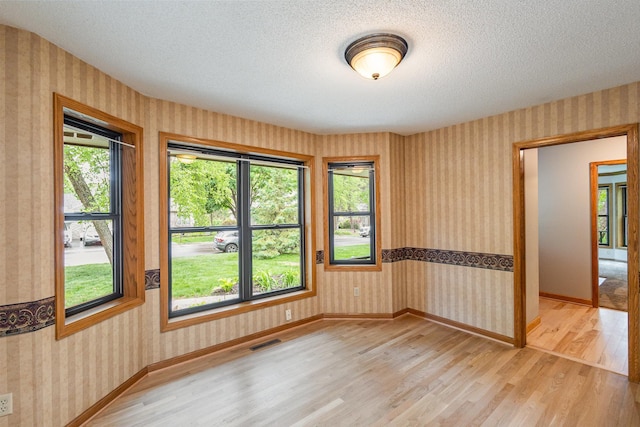 8762 Highwood Way, Apple Valley, MN 55124 - unfurnished room featuring wallpapered walls, light wood-type flooring, a textured ceiling, and baseboards