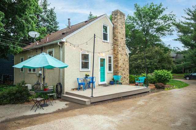 4830 29th Ave S, Minneapolis, MN 55417 - back of house featuring stucco siding, a wooden deck, a chimney, and a patio area