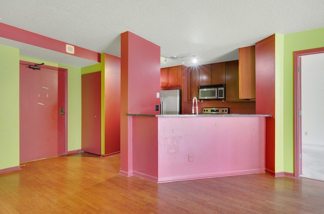 401 1st St Unit 401, Minneapolis, MN 55401 - kitchen with stainless steel appliances, light wood-type flooring, track lighting, a peninsula, and a textured ceiling