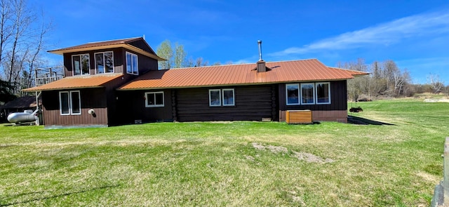 rear view of property featuring a yard and metal roof
