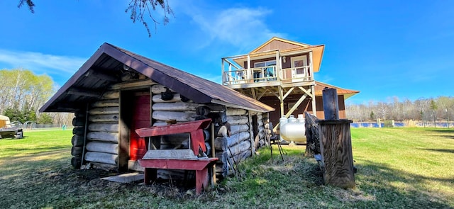 view of side of home with a lawn, log exterior, and an outbuilding