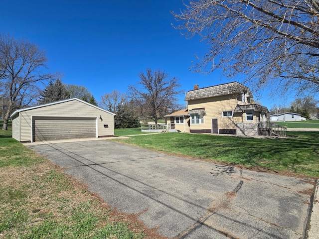 view of side of home with a detached garage, an outbuilding, a chimney, and a yard
