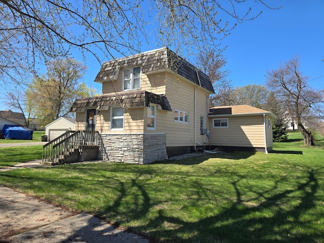 view of side of home featuring a yard, mansard roof, an outdoor structure, and stone siding