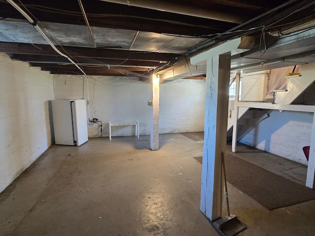unfinished below grade area featuring freestanding refrigerator