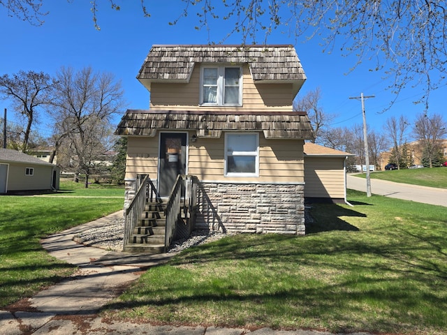 view of front facade with mansard roof, stone siding, and a front lawn