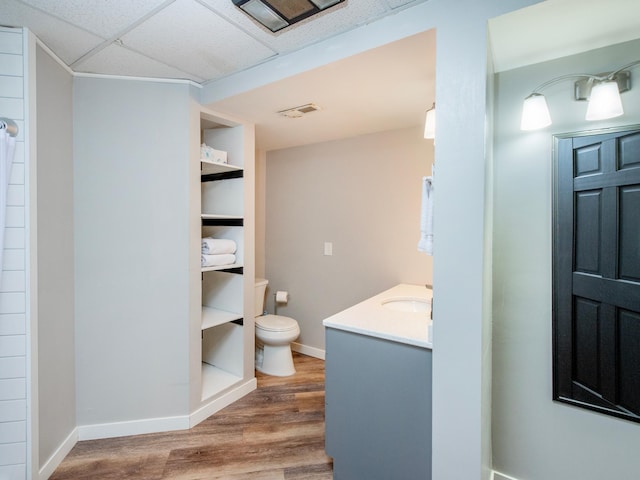 2415 Edgerton St, Little Canada, MN 55117 - full bathroom with toilet, wood finished floors, vanity, baseboards, and a paneled ceiling