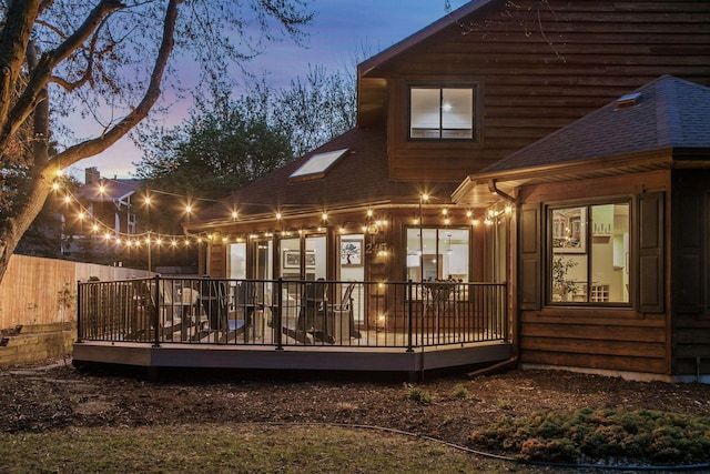 2415 Edgerton St, Little Canada, MN 55117 - back of property at dusk with a shingled roof, fence, and a wooden deck
