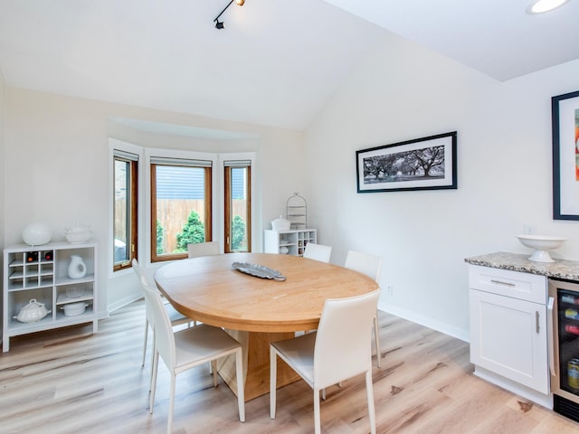 2415 Edgerton St, Little Canada, MN 55117 - dining area featuring beverage cooler, light wood-type flooring, baseboards, vaulted ceiling, and track lighting