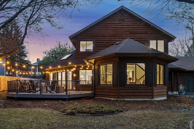 2415 Edgerton St, Little Canada, MN 55117 - back of house at dusk featuring a shingled roof, a deck, and a sunroom