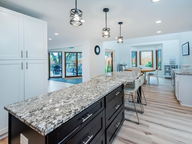 2415 Edgerton St, Little Canada, MN 55117 - kitchen with white cabinetry, a center island, recessed lighting, light stone countertops, and light wood-style flooring
